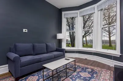 a living room with a blue couch and windows at Flats on Front - Riverfront Gem Fast Wi-Fi 1F in Harrisburg