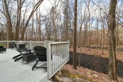 a wooden deck with two chairs and a fence at 30 Day Minimum Stay - Private Creekside Solace in East Stroudsburg