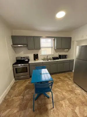 a kitchen with a blue table in front of a refrigerator at 4 Bedroom Apartment in Hillside