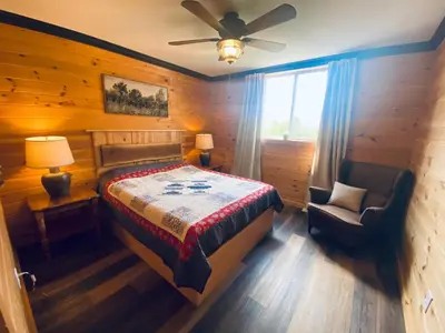 a bedroom with a bed and a chair and a window at The Lodge by Towanda and Sayre PA in Ulster