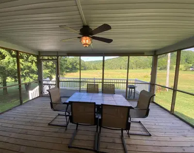 a table and chairs on a porch with a ceiling fan at StoneBrook Haven near Guthrie RPH Towanda Campus in Ulster