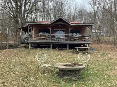 a house with a table and two chairs in a field at Willow Point Cabin Brenchly Lake in Ulster