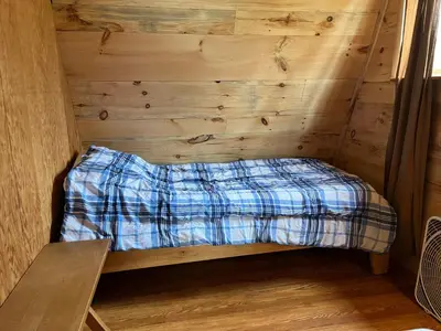 a bed in a room with a wooden wall at Willow Point Cabin Brenchly Lake in Ulster