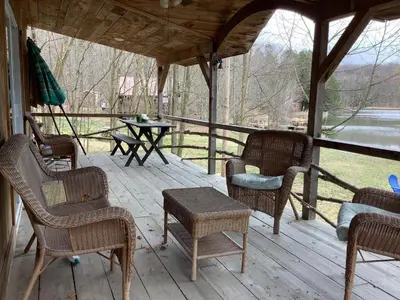 a porch with wicker chairs and a table and a tableearcher at Willow Point Cabin Brenchly Lake in Ulster