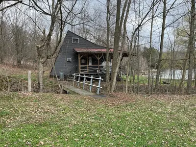 a small house with a porch and a wooden ramp at Willow Point Cabin Brenchly Lake in Ulster