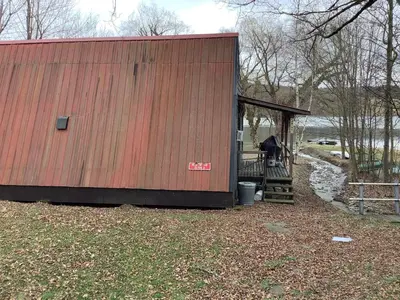 a large building with a porch and a fence at Willow Point Cabin Brenchly Lake in Ulster