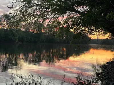 a view of a lake with the sunset in the background at Lakeside Tiny Cozy Retreat in Ulster