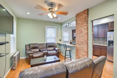 a living room with leather furniture and a brick wall at Jersey City Apartment with Game Room 7 Mi to NYC! in Jersey City