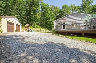 a house with a gravel driveway next to a building at Large Private House on 5 Wooded Acres. Total Privacy! in Hackettstown