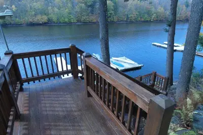 a wooden deck with a boat on a lake at Modern Chalet with Hot Tub and Lake Access in Monticello