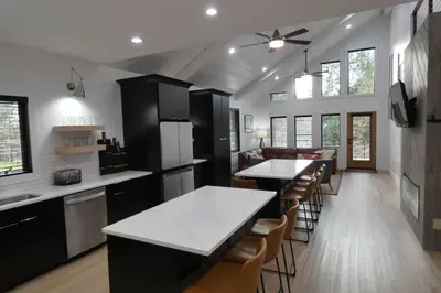 a kitchen with white counter tops and bar stools at Modern Chalet with Hot Tub and Lake Access in Monticello