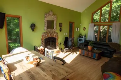 a living room with a table and a fireplace at Whimsical Lakefront Chalet in Monticello
