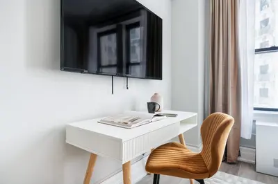 a white desk with a chair and a tv on a wall at 73-1104 New Studio UWS Doorman Gym in New York