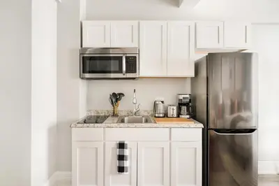 a kitchen with white cabinets and a stainless steel refrigerator at 73-1104 New Studio UWS Doorman Gym in New York