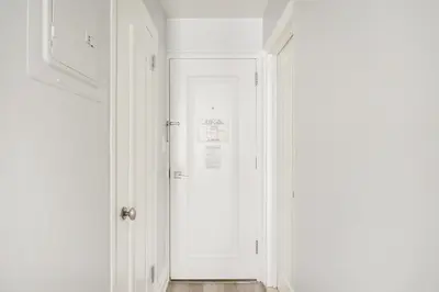 a white door in a white hallway with a wooden floor at 73-1104 New Studio UWS Doorman Gym in New York