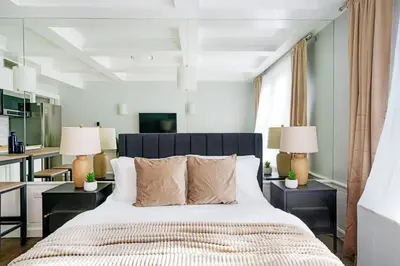a bedroom with a large bed with two tables and two lamps at 73-1104 New Studio UWS Doorman Gym in New York
