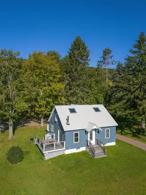 a blue house on a lawn with trees at Chambers Hollow in Walton