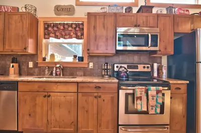 a kitchen with wooden cabinets and a stove and microwave at Whispering Pines Retreat in Albrightsville
