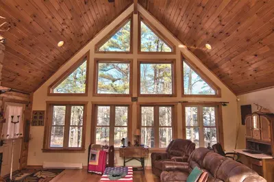 a living room with large windows and leather furniture at Whispering Pines Retreat in Albrightsville