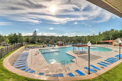 a swimming pool with blue chairs in a park at 3BR, Lakeview, Hot Tub, Nintendo Switch - Deer Haven Poconos Retreat in Tobyhanna