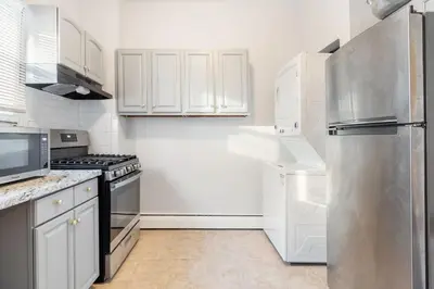 a kitchen with white cabinets and a stainless steel refrigerator at CLINTON HILLS - Newark in Newark
