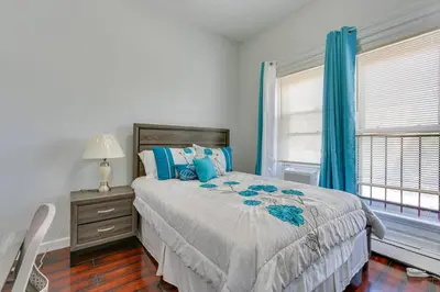 a bedroom with a bed and a window with blue curtains at CLINTON HILLS - Newark in Newark