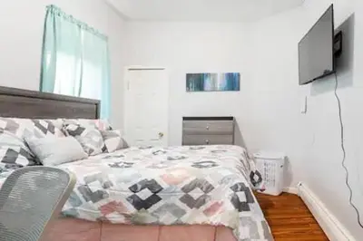 a bedroom with a bed and a television on the wall at CLINTON HILLS - Newark in Newark