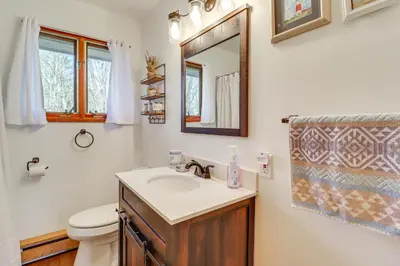 a bathroom with a sink and a toilet and a mirror at Lovely Tobyhanna Getaway with Game Room and Fire Pit! in Tobyhanna