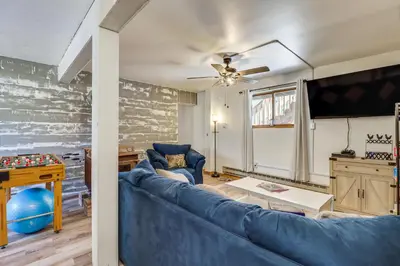a living room with a blue couch and a flat screen tv at Lovely Tobyhanna Getaway with Game Room and Fire Pit! in Tobyhanna