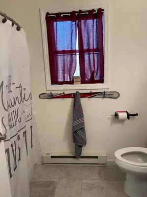 a bathroom with a toilet and a window with skis at Casa di Montagna/5BR/3Bath/NearResorts/PetsAllowed in Pocono Lake