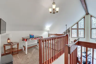 a living room with a staircase and a table at Serene Poconos Cabin with Hot Tub and Beach Access! in Albrightsville