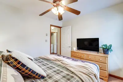 a bedroom with a bed with a ceiling fan and a tv at Serene Poconos Cabin with Hot Tub and Beach Access! in Albrightsville