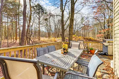 a patio with a table and chairs and trees at Serene Poconos Cabin with Hot Tub and Beach Access! in Albrightsville