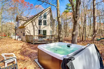 a jacuzzi tub in front of a house at Serene Poconos Cabin with Hot Tub and Beach Access! in Albrightsville