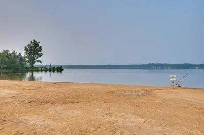a sandy beach next to a body of water at Serene Poconos Cabin with Hot Tub and Beach Access! in Albrightsville
