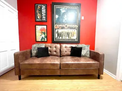 a brown couch in a room with a red wall at Larry's Lancaster Landing: with fully-fenced yard in Lancaster