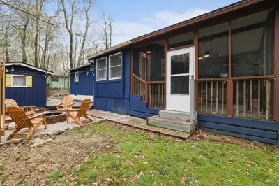 a blue house with two chairs and a door at 2BR Cottage with Hot Tub in Tobyhanna