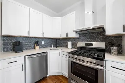 a kitchen with white cabinets and a stove top oven at Big City Living: Elegant Apartment with NYC Vibes in Jersey City