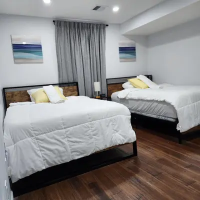 a bedroom with two beds with white sheets and yellow pillows at The Luxurious loft in Newark