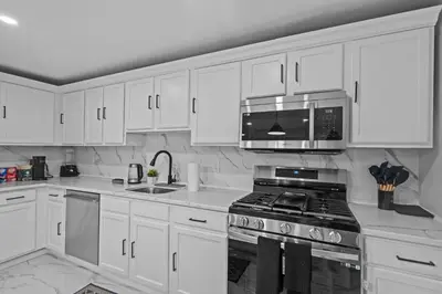 a white kitchen with a stove and a microwave at The Luxurious loft in Newark