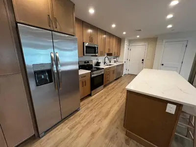 a kitchen with a stainless steel refrigerator and wooden cabinets at Montgomery Modern Luxury Stays in Montgomery