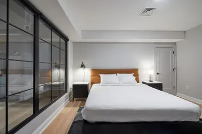 a bedroom with a large white bed and glass walls at Riversuites At The Battery in Philadelphia