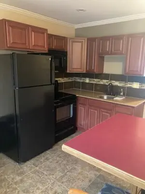 a kitchen with a black refrigerator and wooden cabinets at Williamsport Grandview Hotel in Linden
