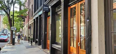 a woman walking down a street in front of buildings at Sosuite at The Loxley - Old City in Philadelphia