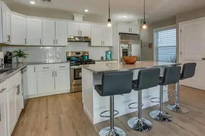a kitchen with white cabinets and a island with bar stools at Modern City Getaway Near Downtown Newark & NYC in Newark