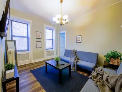 a living room with a blue couch and a table at Charming 1BR Apartment Near NYC Ideal for Urban Explorers in Jersey City