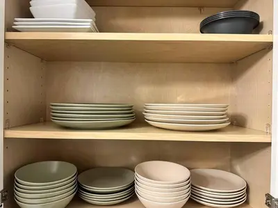 a cabinet filled with plates and bowls at Cozy 3 BR suite, 15 min to NYC &Times Sq in North Bergen