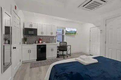 a white bedroom with a bed and a kitchen at New Season Royals, Airport West in Chester