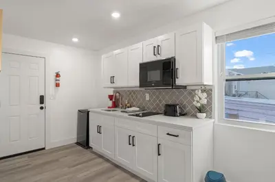 a white kitchen with white cabinets and a window at New Season Royals, Airport West in Chester