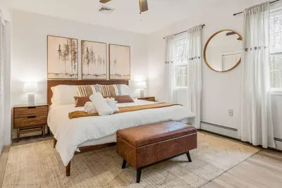 a white bedroom with a large bed and a mirror at Boho Haven Hideaway - Walk to Pool,Theater,Arcades, Firepit, Lake Access in Thornhurst